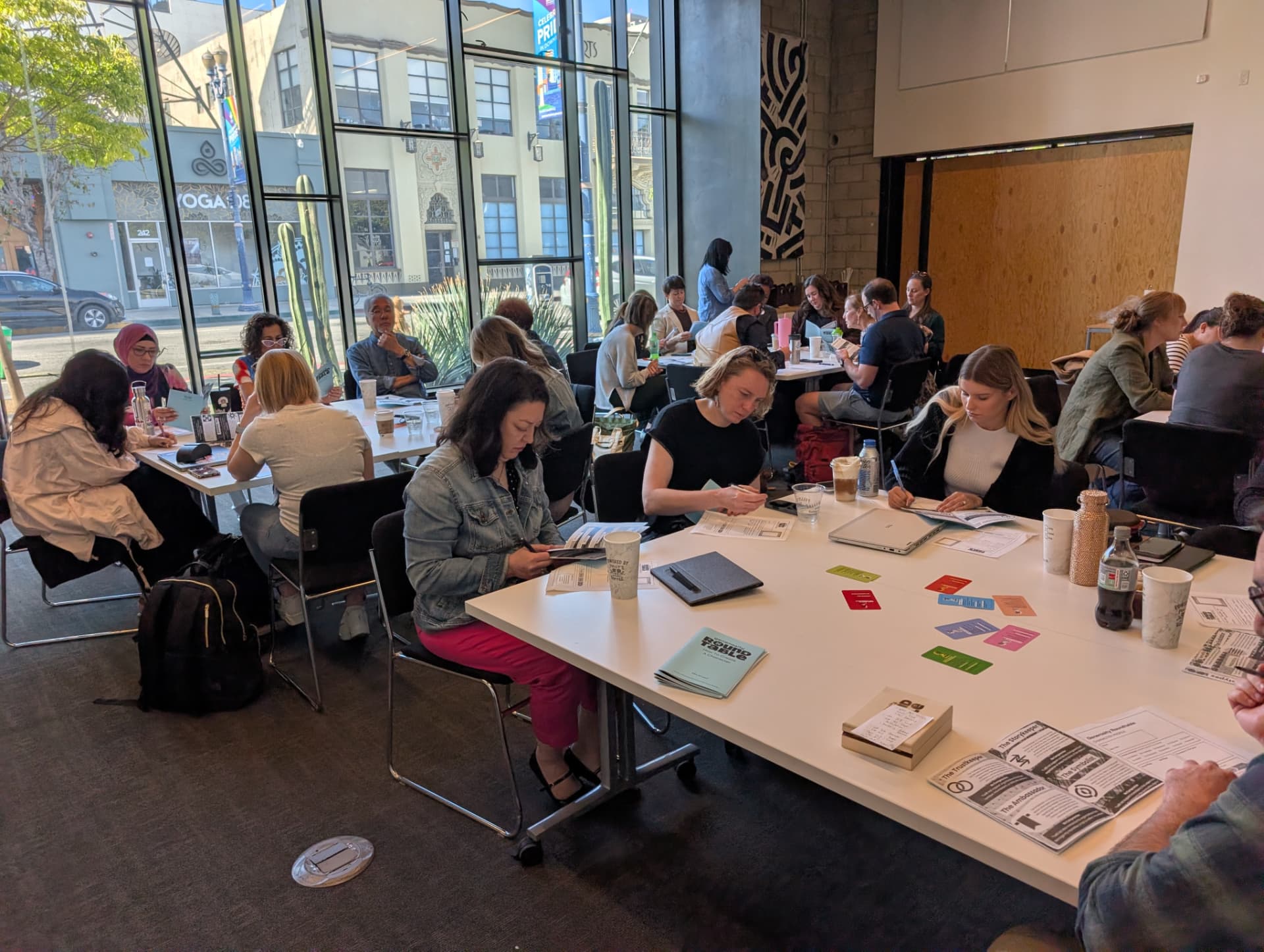 A packed room of players working through character sheets and cards at long tables.