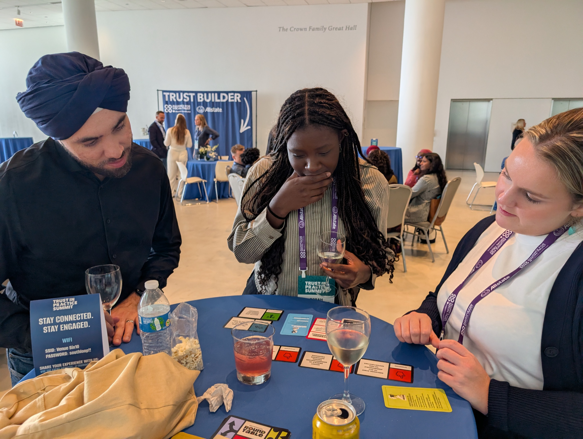 Three players laughing around a table of Generosity Roundtable cards at the Trust in Practice Summit.