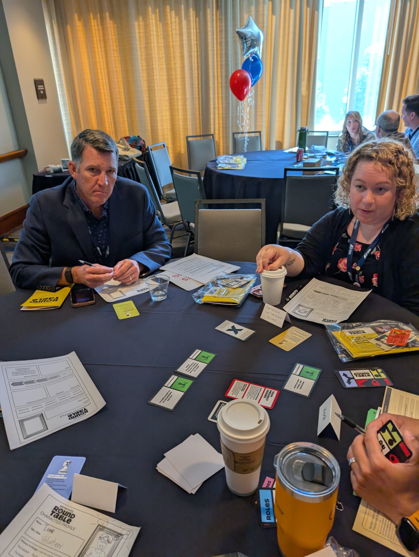 Two players filling out character profiles at a conference table.