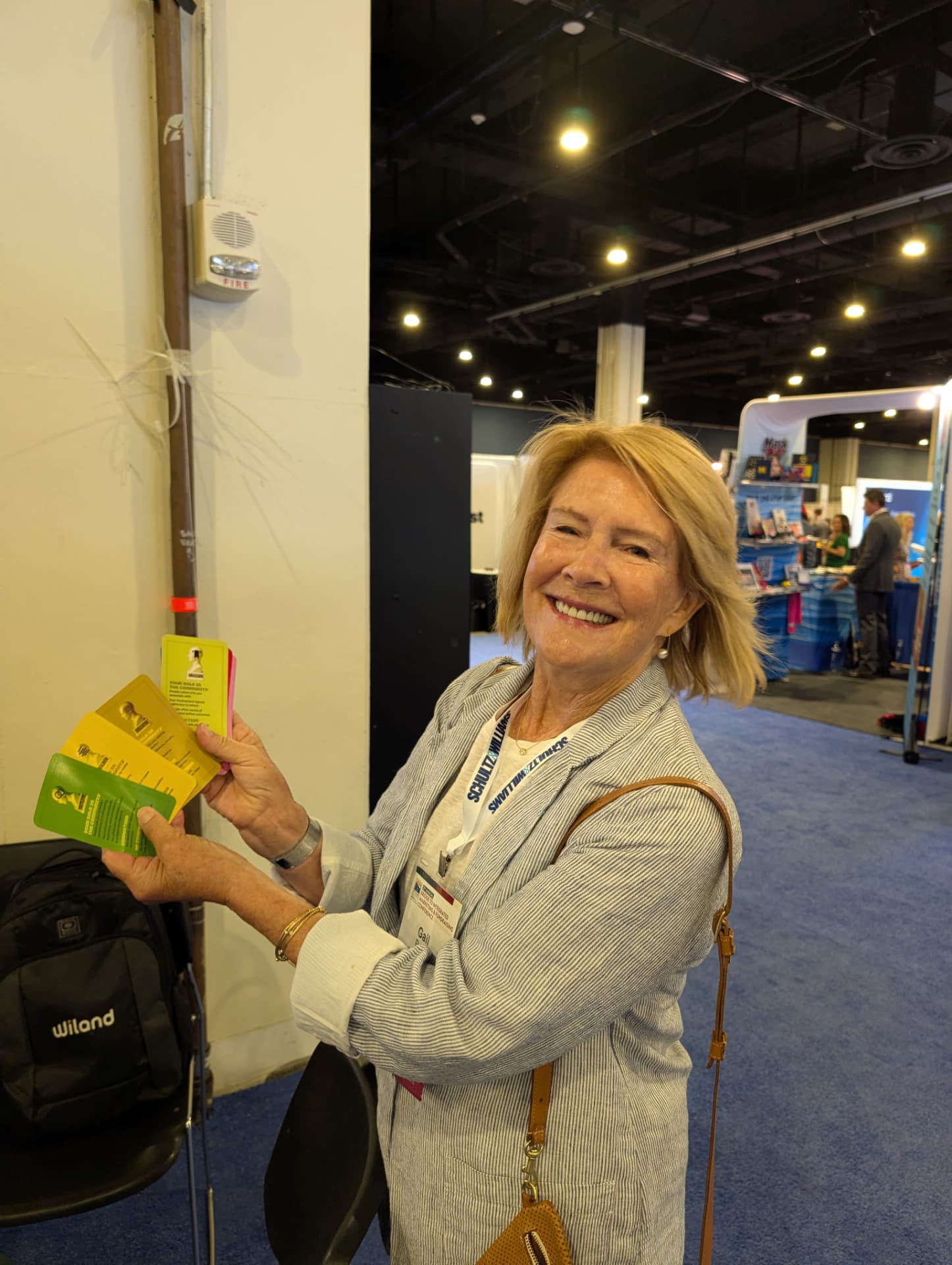 A conference attendee smiles while holding a fan of colorful Generosity Roundtable cards.